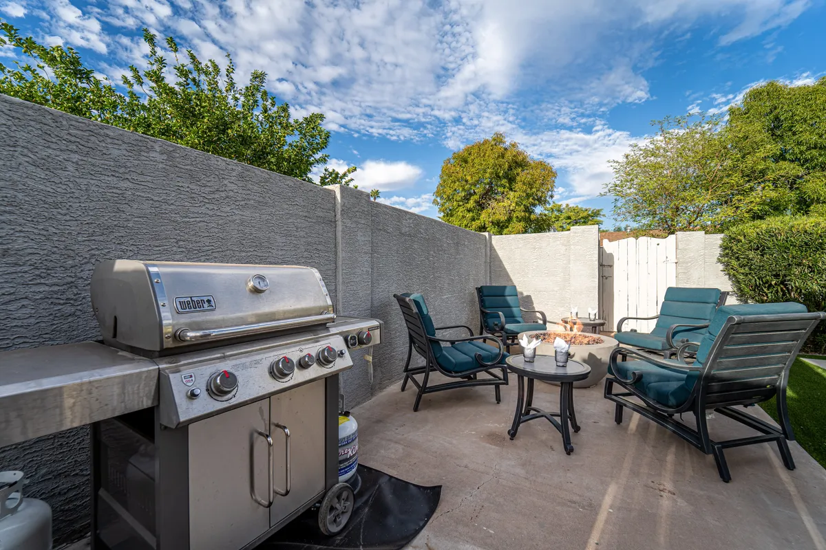 An inviting backyard setup featuring a grill, a cozy seating area, and a fire pit. The outdoor space looks ready for both relaxation and social gatherings, with ample room for a pet to explore or rest after a day of adventure.