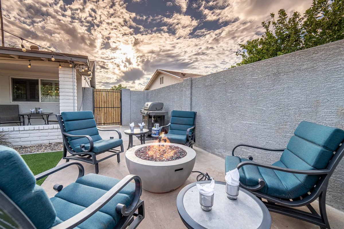 An inviting fire pit surrounded by comfortable outdoor seating, set against a stunning Arizona evening sky. The area exudes warmth and is perfect for socializing, toasting marshmallows, or stargazing after sunset.